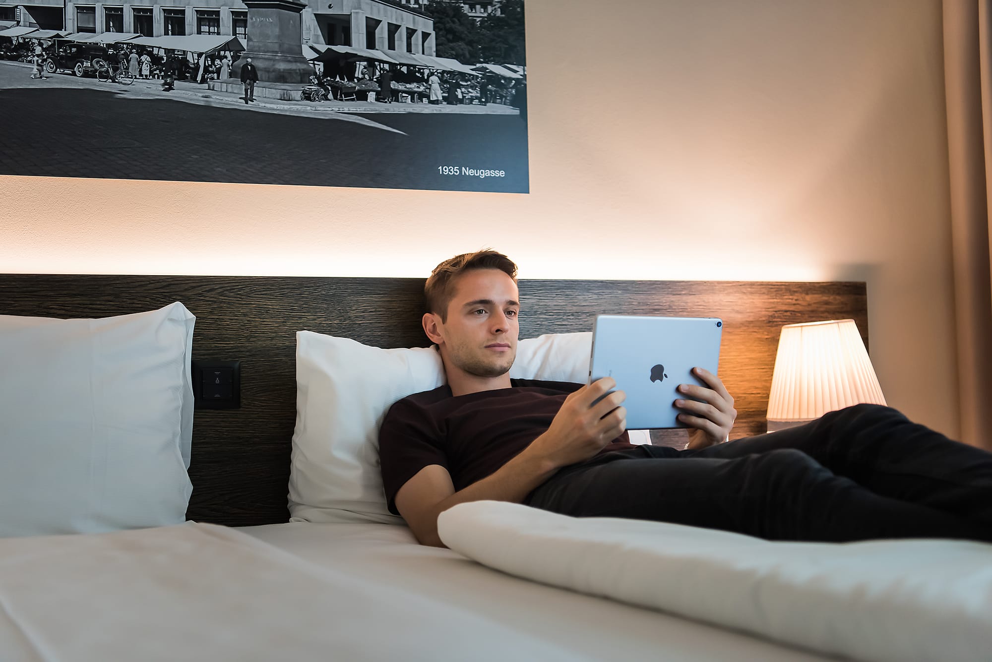 Gast liegt im Bett mit iPad, Hotel one66